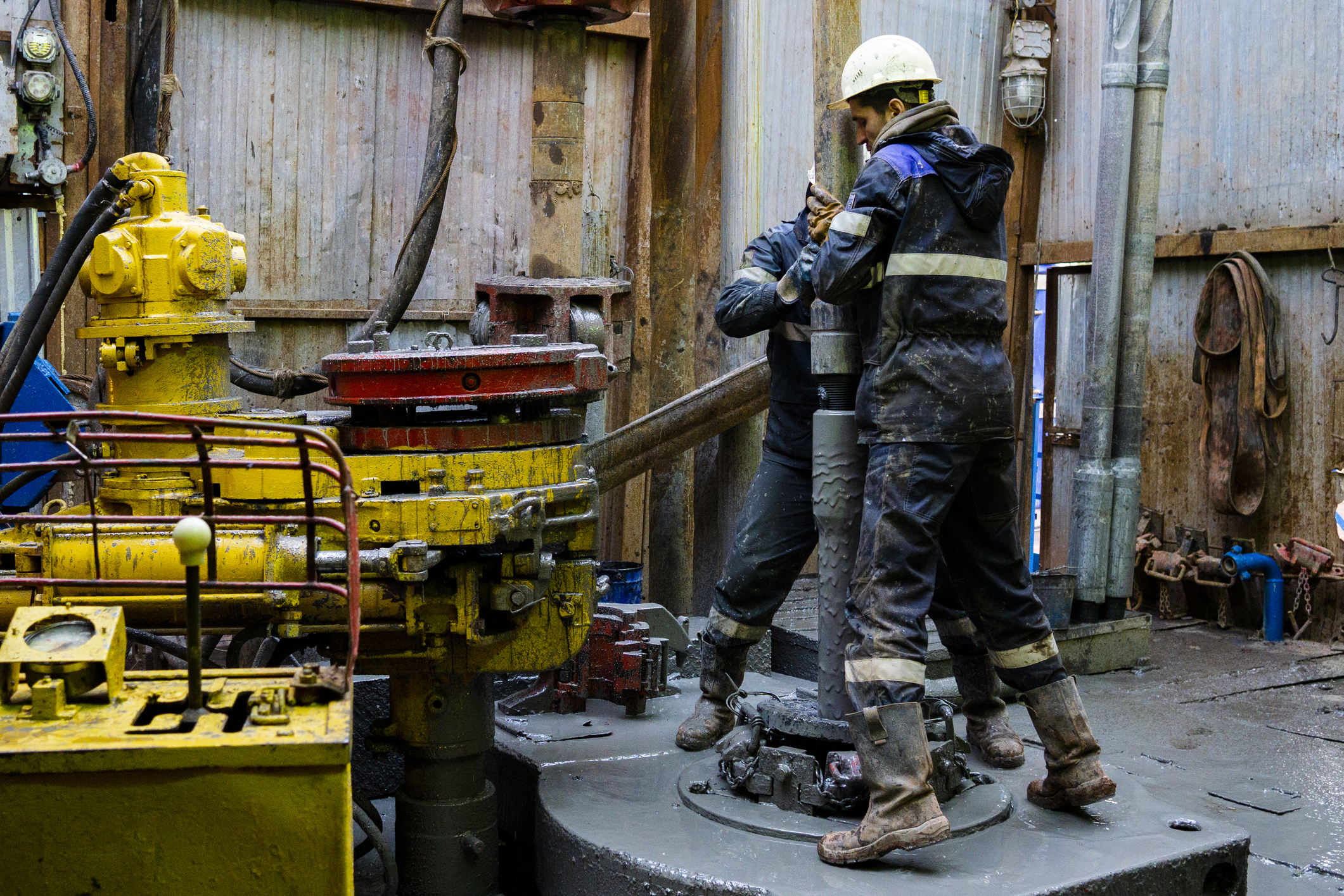 Offshore Oil Rig Worker Prepare Tool And Equipment For Perforation Oil And Gas Well At Wellhead Platform. Making Up A Drill Pipe Connection. A View For Drill Pipe Connection From Between The Stands.